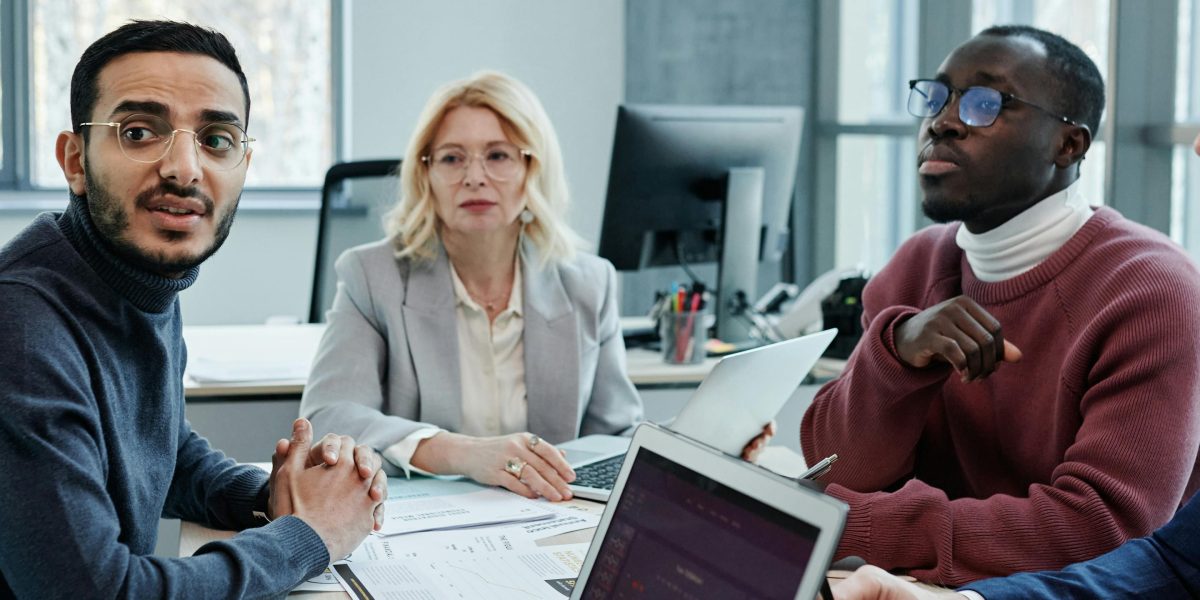 A focused team engaged in a professional discussion, with one member presenting or facilitating a point.
