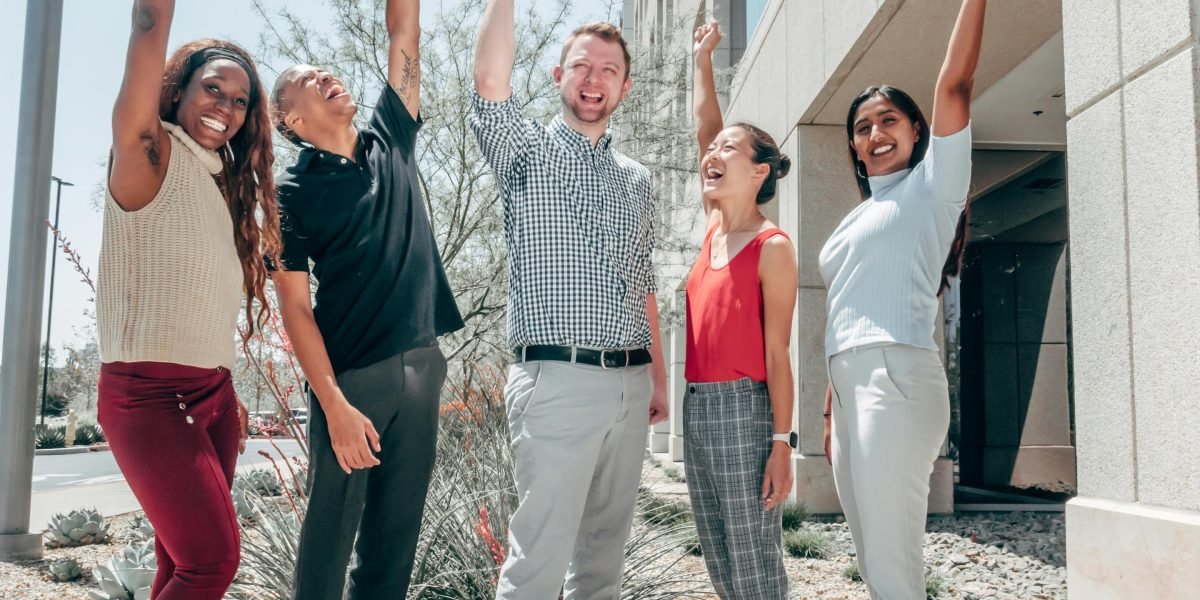 A diverse group of colleagues celebrating a shared success or achievement in a dynamic office setting.