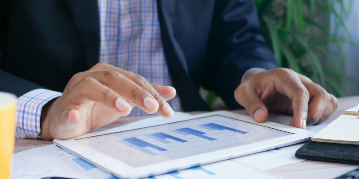 A manager thoughtfully reviewing data charts and reports on a tablet, symbolizing the process of measuring the impact and ROI of team activities.