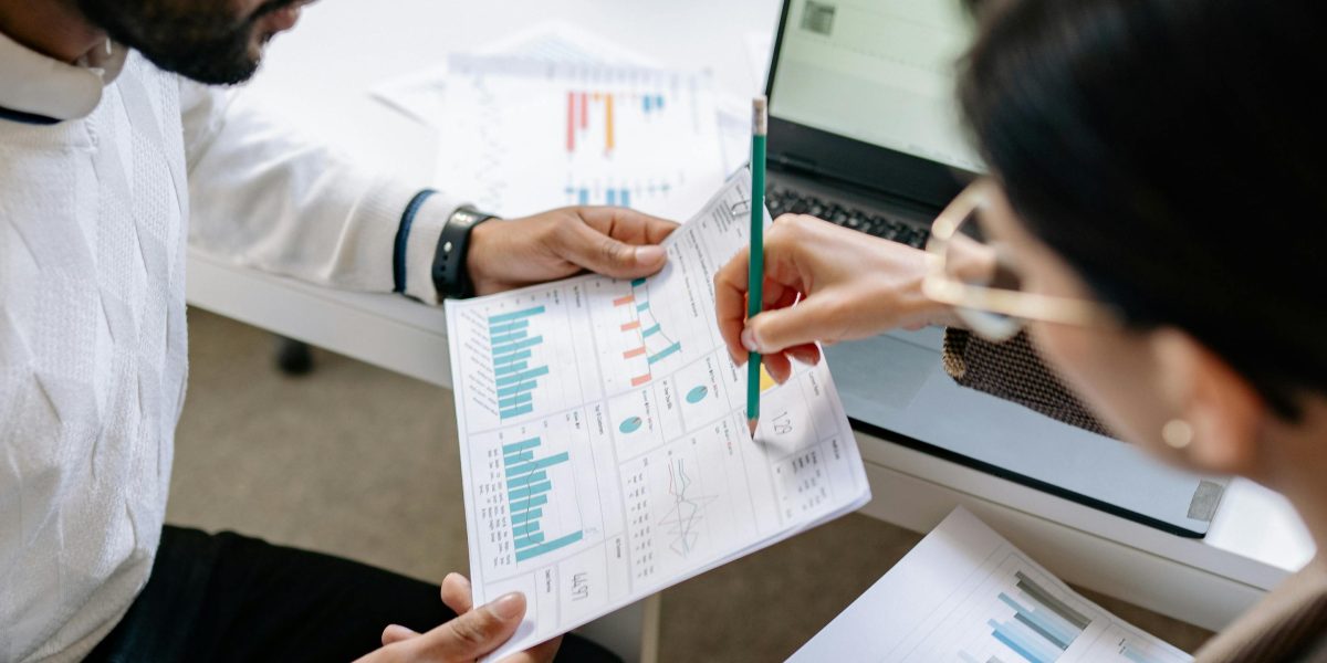 Professionals analyzing charts and data on a screen or printouts, discussing performance metrics and impact.